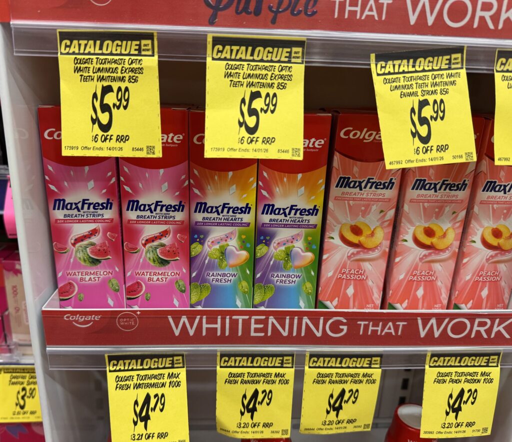 Close-up of Colgate MaxFresh toothpaste price tags at Chemist Warehouse showing AUD 4.79 per 100g tube.