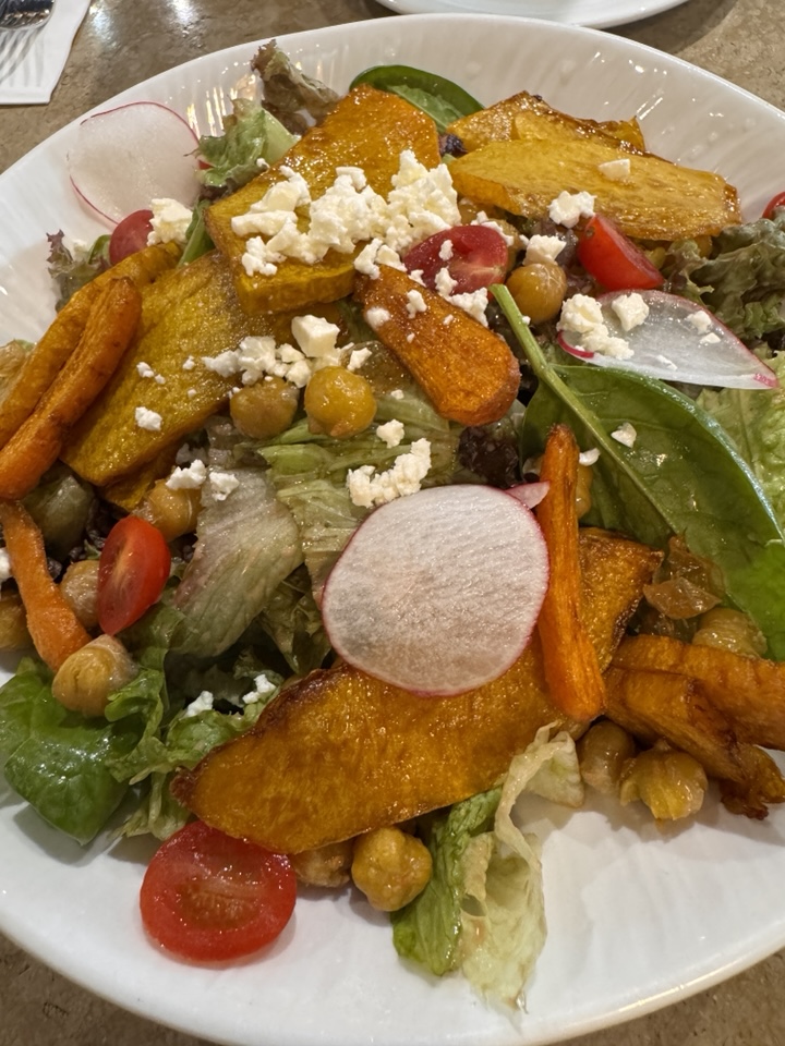 A large bowl of signature pumpkin salad with various fresh vegetables at Roots Bistro.