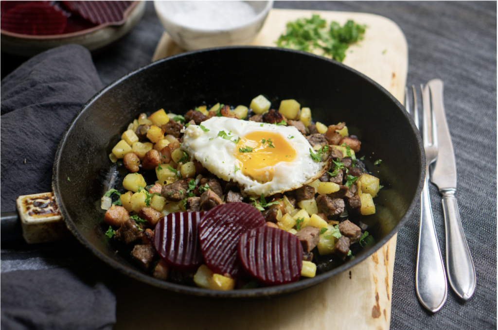 Pytt i Panna, a traditional Swedish dish made with diced potatoes, meat, fried egg, and pickled beets