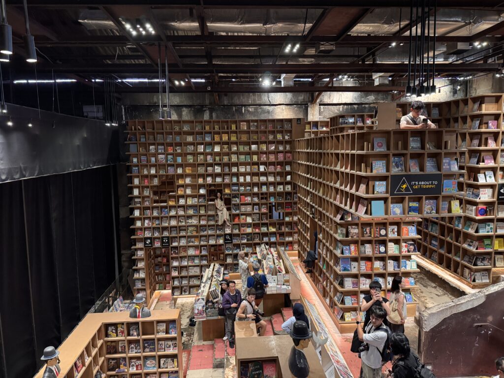 Interior view of BookXcess at REXKL with towering bookshelves, open walkways, and visitors browsing books.