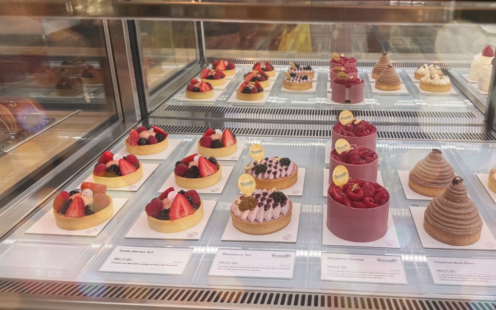 Pastry display case at KLCG Bakery showing fruit tarts and assorted desserts.