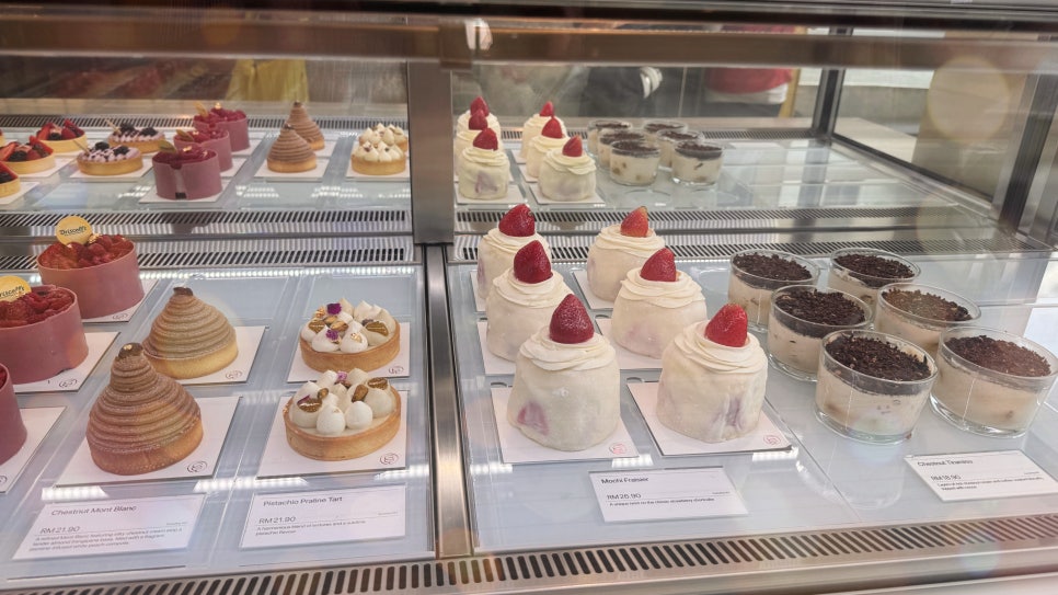 Strawberry mochi cake displayed in a glass pastry case at KLCG Confectionery & Bakery.