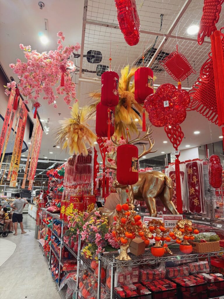 Lunar New Year decoration display with lanterns, gold deer statue, and red ornaments in Malaysia retail store.