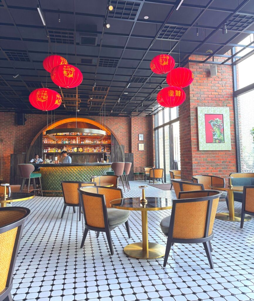 Interior of JANN bar showing the bar counter with emerald green tiles and rattan seating.
