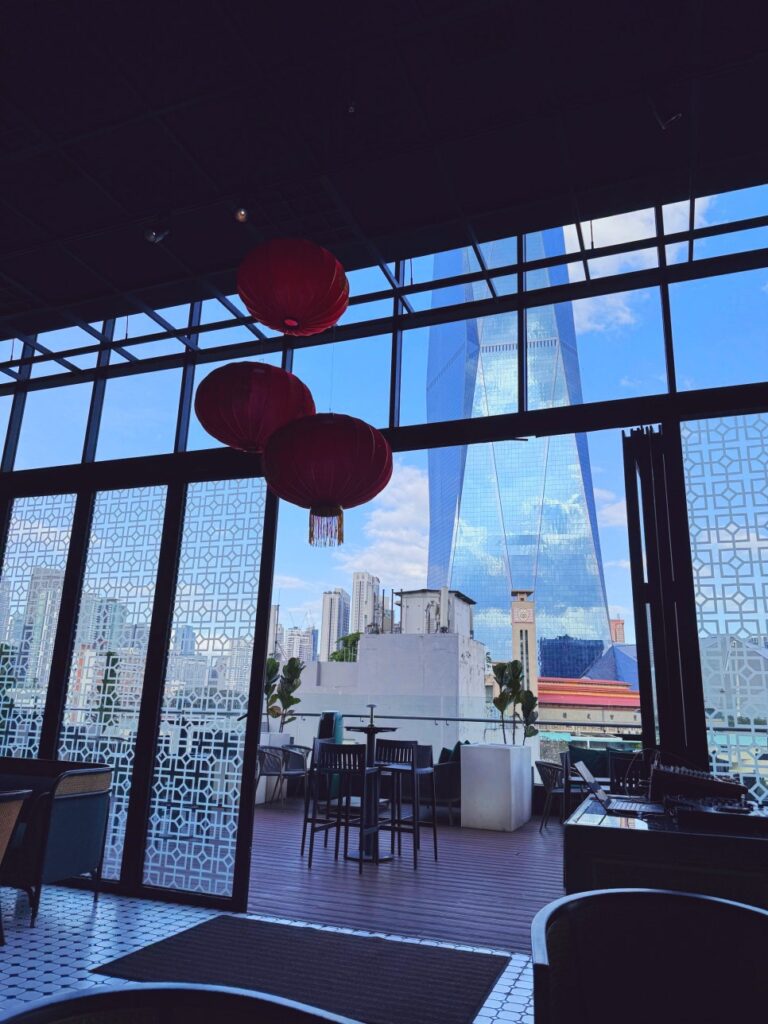 Outdoor terrace bar seating area at JANN with high tables and chairs facing the Kuala Lumpur city skyline at night.