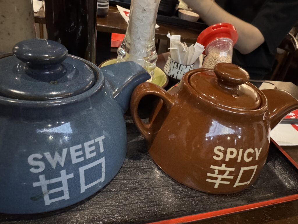 Variety of condiments at Tonkatsu by Ma Maison, including signature Sweet and Spicy sauces, grated radish, and salt.