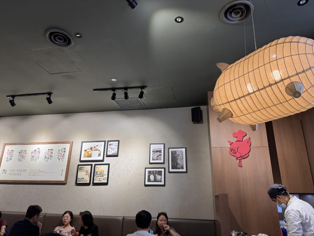 Cozy interior of Tonkatsu by Ma Maison at 163 Retail Park featuring unique pig-shaped lampshades and Japanese-style wooden decor.